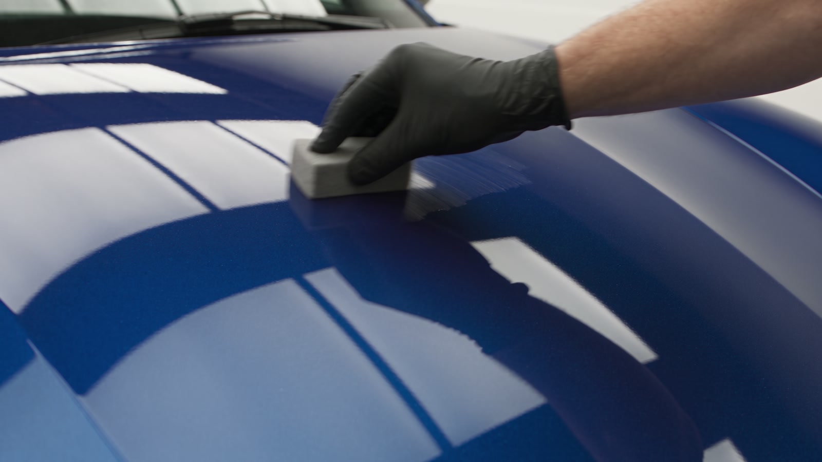 Ceramic coating being applied to a deep-blue hood